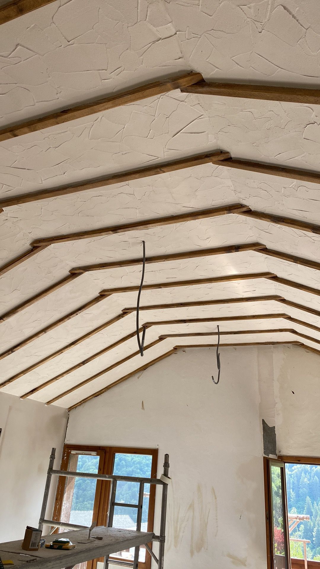 Traditional lime plaster applied between exposed timber beams on a vaulted ceiling